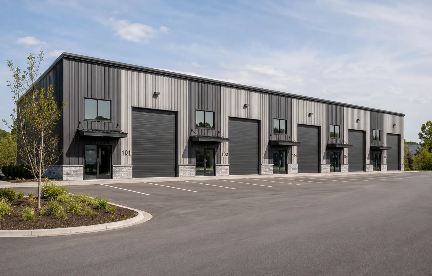 A row of new small-bay units with grade-level roll-up doors and parking out front.